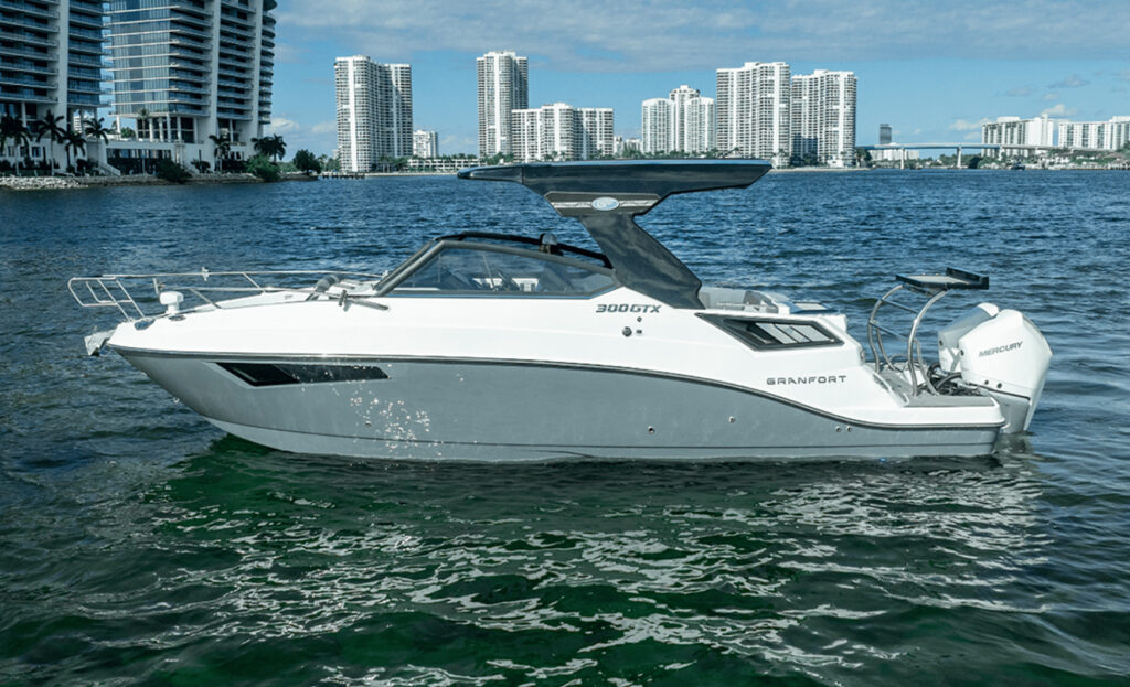 Side view of the Granfort 300 GTX white hull and black hardtop against a city skyline