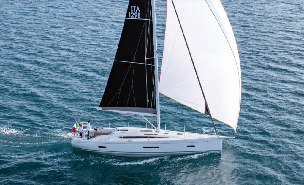 Aerial view of the Italia Yachts IY 12.98 Bellissima sailing with its black mainsail and large white spinnaker.