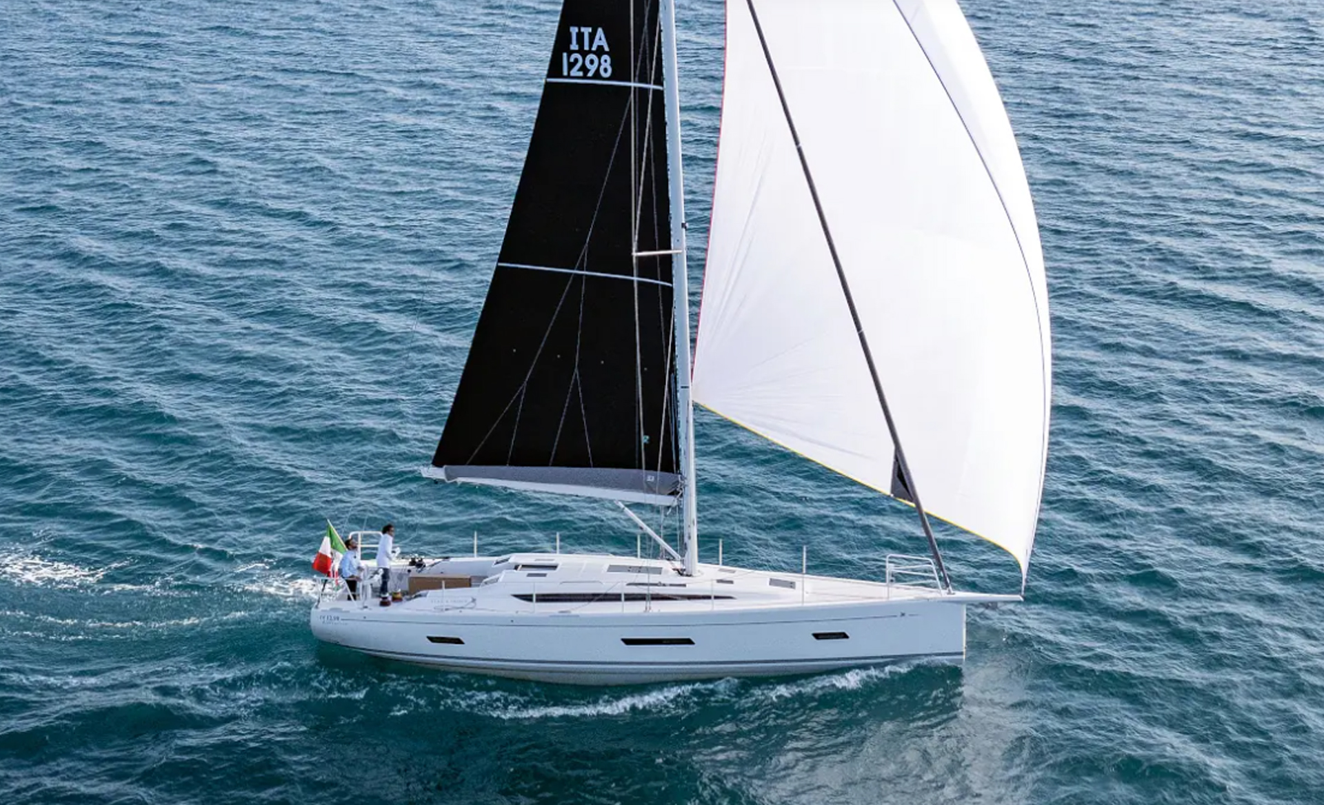 Aerial view of the Italia Yachts IY 12.98 Bellissima sailing with its black mainsail and large white spinnaker.