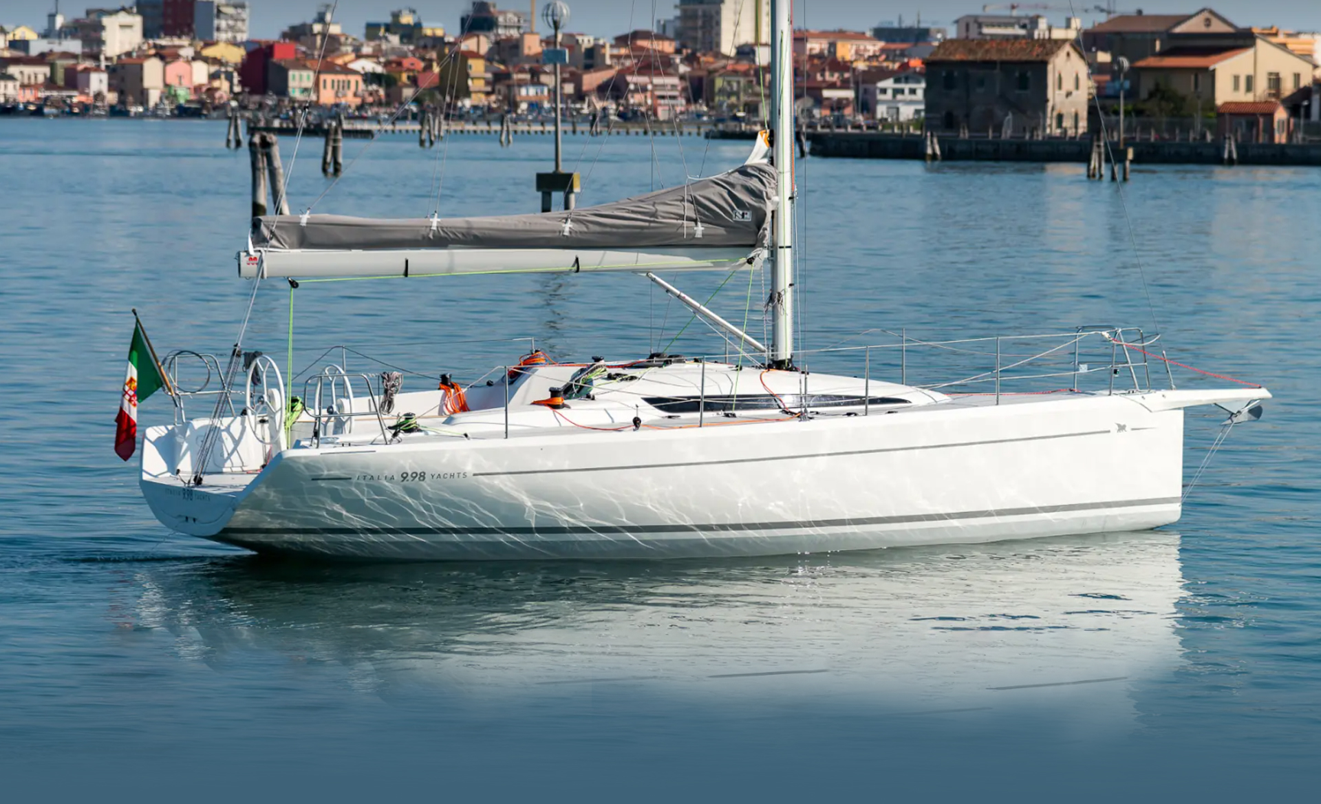 Side profile of the Italia Yachts IY 9.98 Bellissima sailing yacht on the water, showcasing its elegant hull lines and mast.