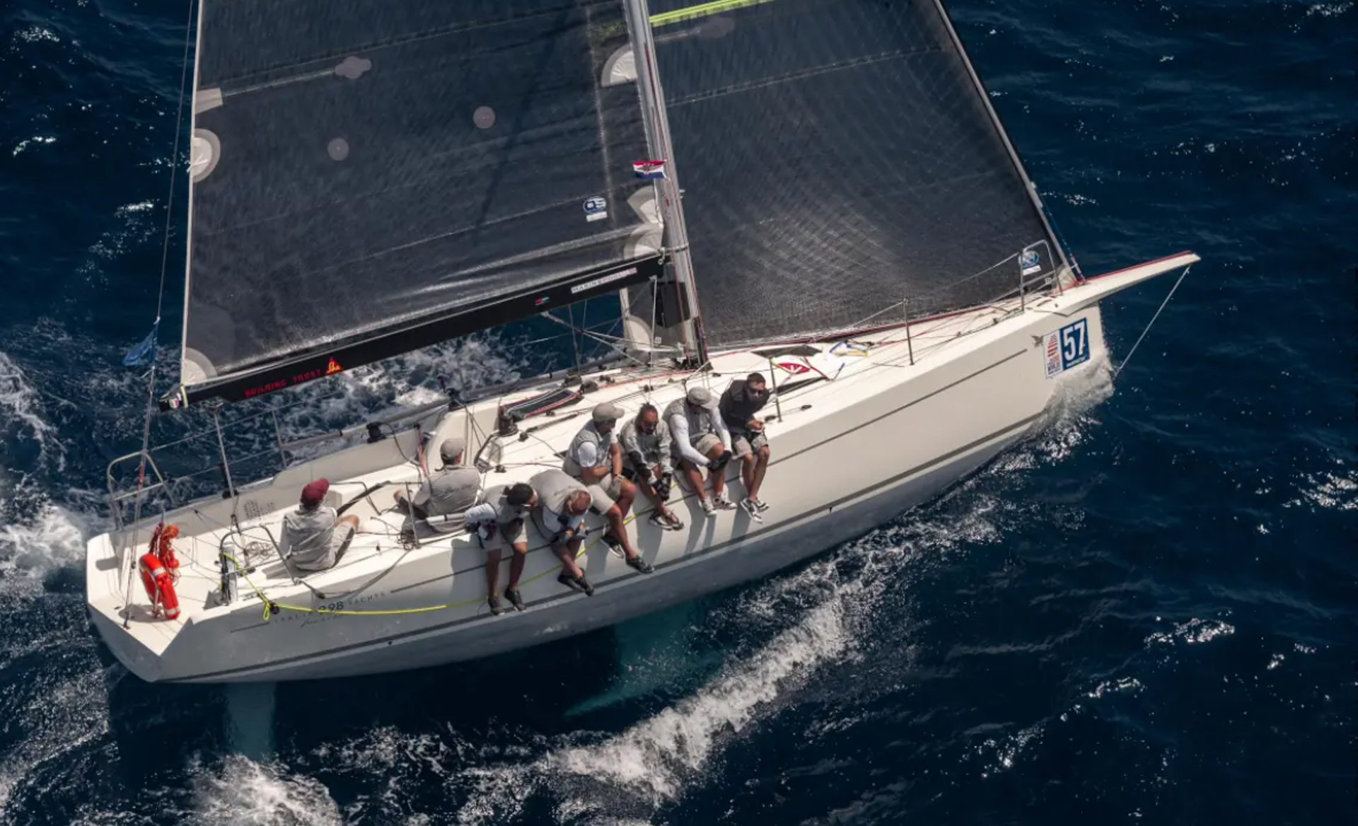 Aerial view of the Italia Yachts IY 9.98 Fuoriserie racing yacht with crew positioned along the deck.