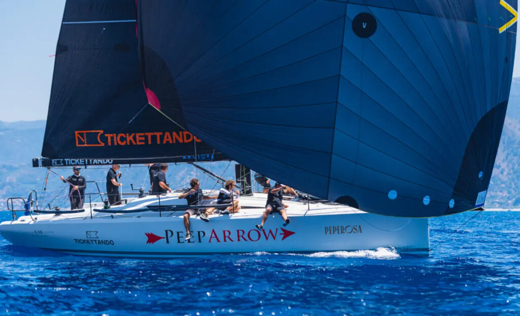 Side view of the Italia Yachts IY 11.98 Fuoriserie sailing yacht racing with a large blue spinnaker.