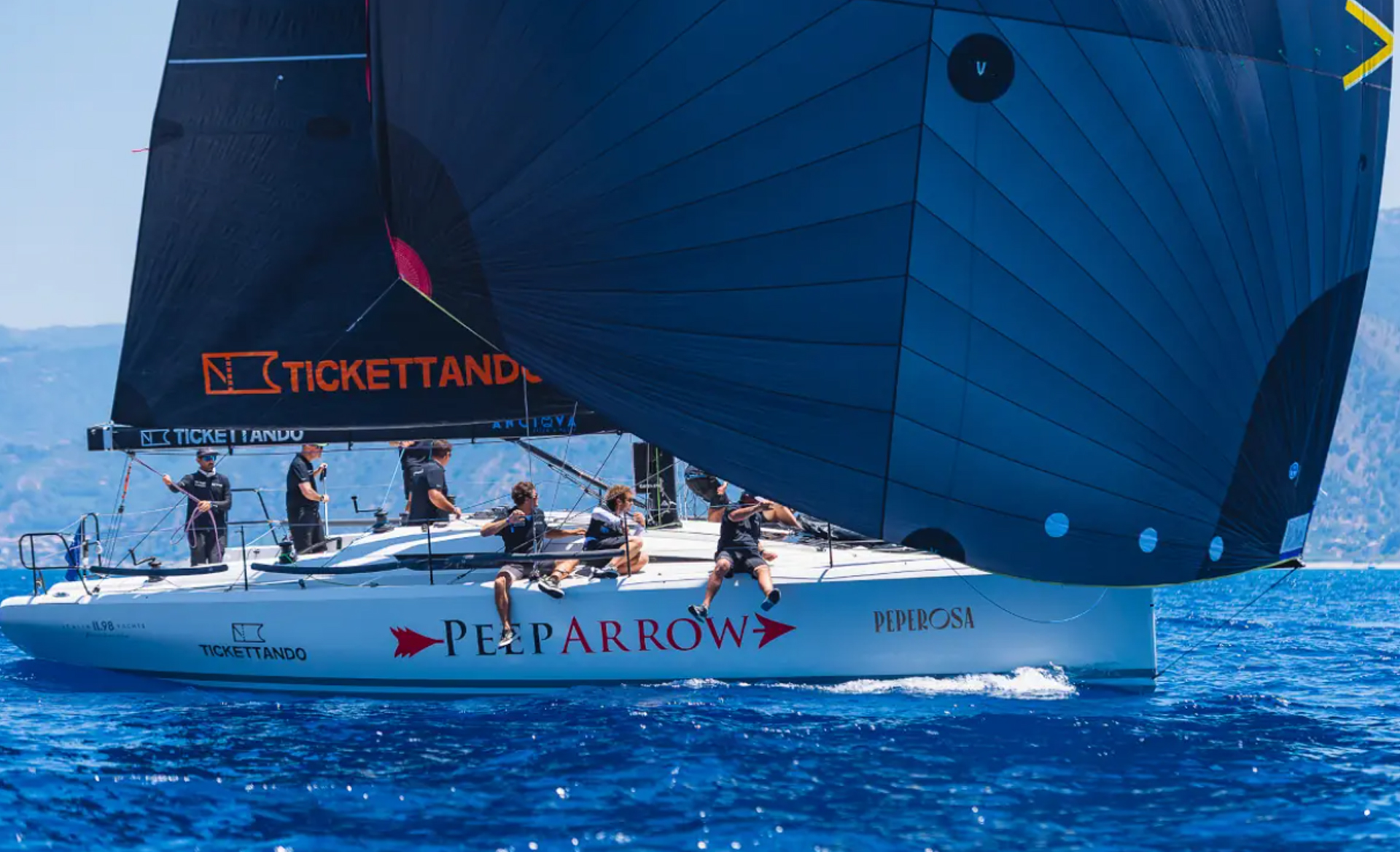 Side view of the Italia Yachts IY 11.98 Fuoriserie sailing yacht racing with a large blue spinnaker.