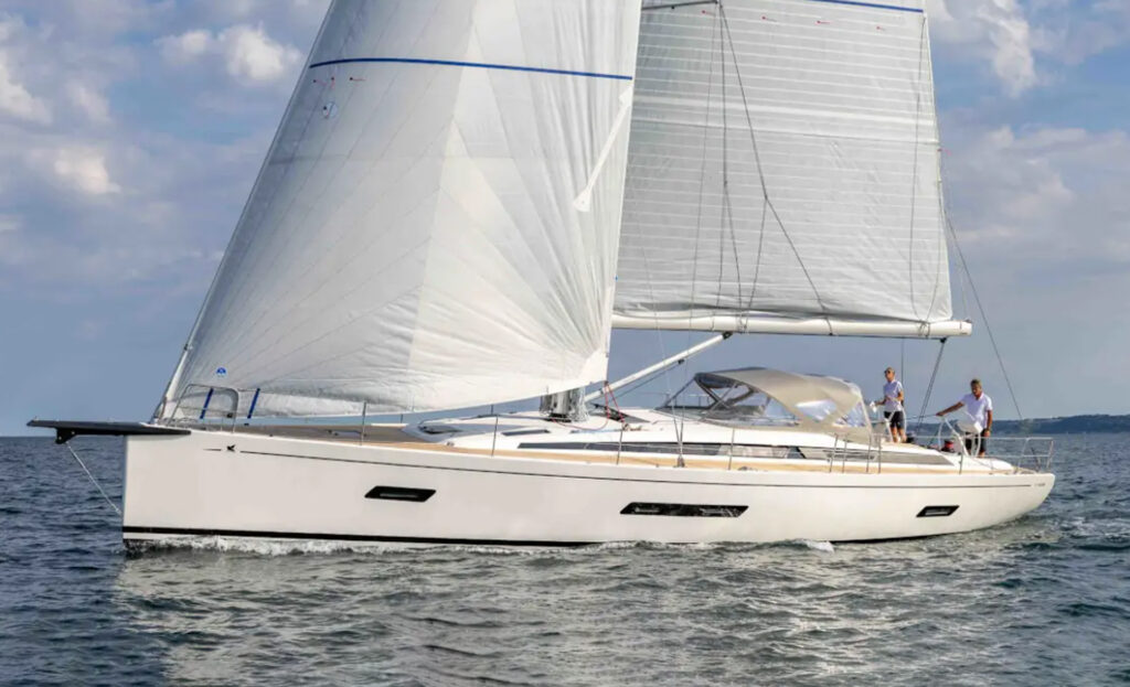 Side profile of the Italia Yachts IY 16.98 Bellissima sailing yacht with its sails raised and streamlined white hull.